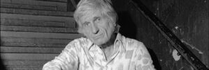 Photo noir et blanc de l'arrangeur Gil Evans, assis dans un escalier. Site de vente de vinyles Everything Jazz.