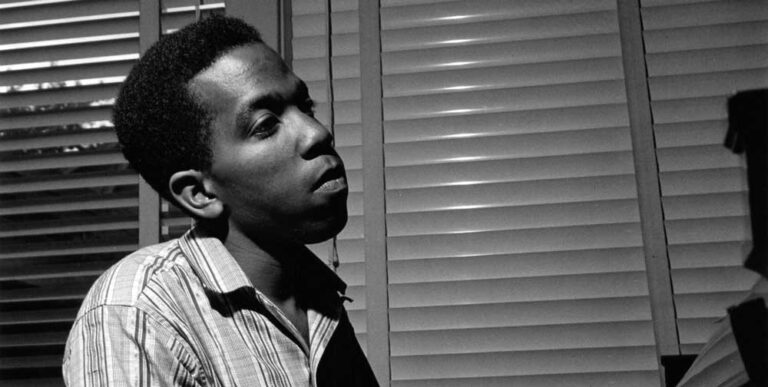 Photo noir et blanc de Sonny Clark, l'air rêveur, jouant du piano en intérieur. Site de vente de vinyles jazz Everythnig Jazz.