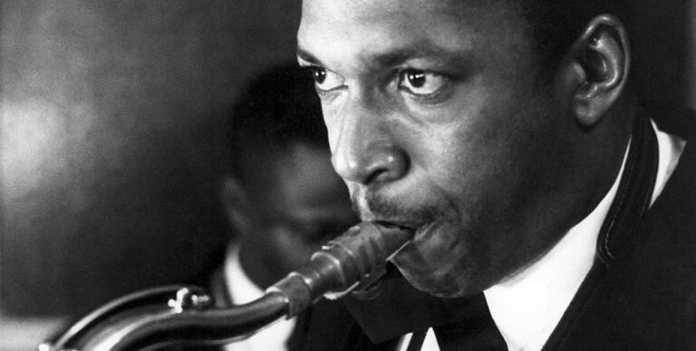 photo noir et blanc en gros plan de John Coltrane, en costume et noeud papillon, soufflant dans son saxophone. Achetez le vinyle 