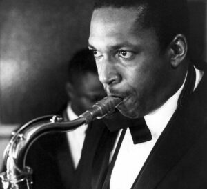 photo noir et blanc en gros plan de John Coltrane, en costume et noeud papillon, soufflant dans son saxophone. achetez le vinyle 